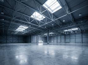 Interior de galpão logístico com estrutura metálica de cobertura e piso industrial de concreto